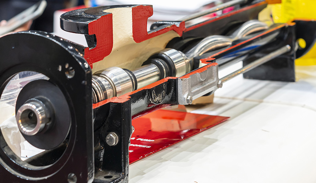 This image shows a detailed view of machinery, featuring shiny metal rods, gears, and a red component, likely part of an industrial or mechanical system.