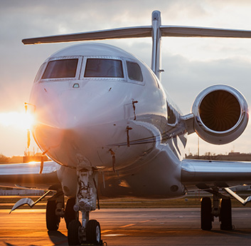 A private jet is on the tarmac at sunset, its sleek design highlighted by the warm sunlight, with clear skies in the background.