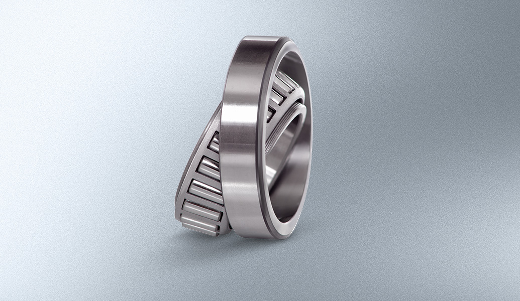 The image shows a detailed metallic tapered roller bearing on a gradient gray background, emphasizing its industrial design and precision engineering.