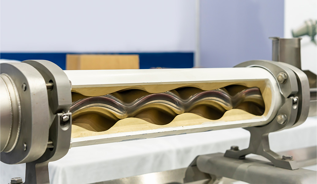 This image depicts an industrial dough sheeter or roller machine, likely used in baking or pasta making, with dough being flattened and shaped between rollers.