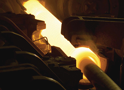 The image shows an industrial setting with machinery casting hot, glowing metal, possibly steel, in a foundry, with fiery orange and yellow colors dominating the scene.