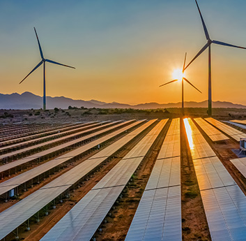 This image shows a renewable energy setup with rows of solar panels and wind turbines against a sunset sky, symbolizing sustainable power generation.